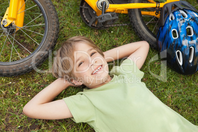 Smiling relaxed boy with bicycle at park