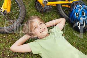Smiling relaxed boy with bicycle at park