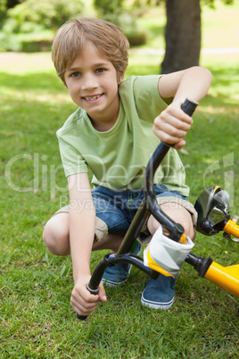 Smiling young boy with bicycle at park