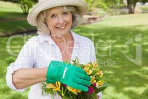 Portrait of a mature woman holding plant at park
