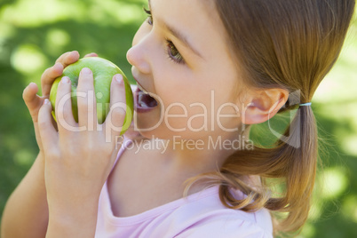 Close-up of a girl eating apple in park