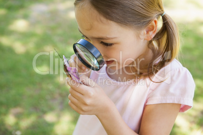 Girl examining butterfly with magnifying glass at park