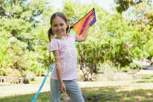 Happy young girl holding kite at park