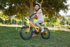 Smiling young girl riding bicycle at park