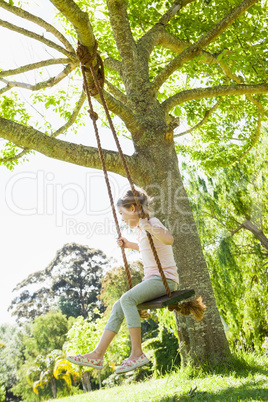 Young girl sitting on swing at park