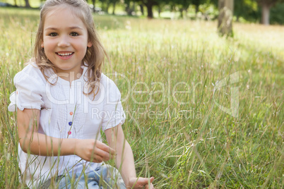 Smiling relaxed young girl sitting in field