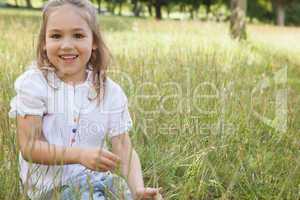 Smiling relaxed young girl sitting in field