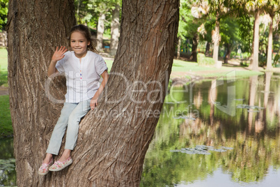 Portrait of a smiling girl sitting on tree at park