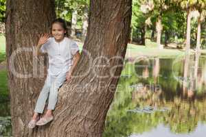 Portrait of a smiling girl sitting on tree at park