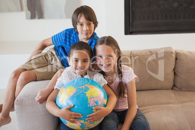 Portrait of happy kids with globe in living room