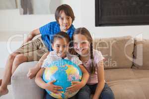 Portrait of happy kids with globe in living room