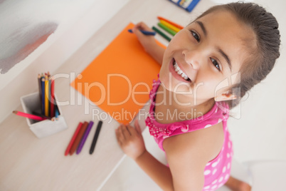 Young girl drawing on orange paper