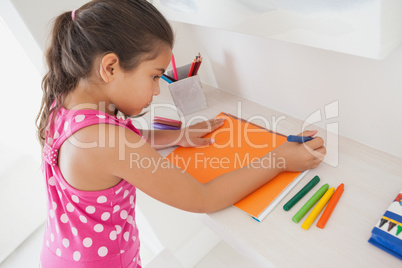 Young girl drawing on orange paper