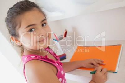 Young girl drawing on orange paper