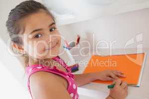 Young girl drawing on orange paper