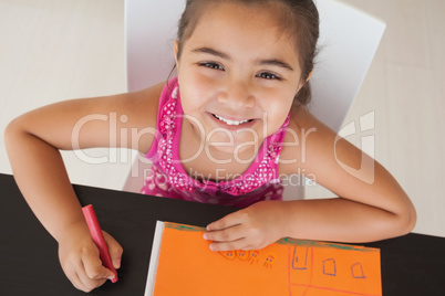 Young girl drawing on orange paper