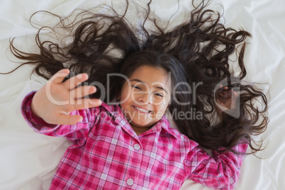 High angle portrait of smiling girl lying in bed