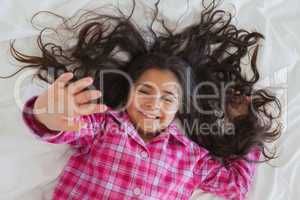 High angle portrait of smiling girl lying in bed