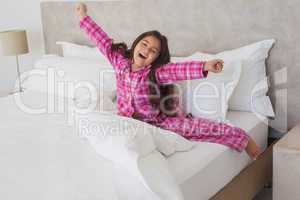 Girl yawning while stretching her arms in bed