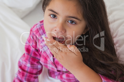 Close-up of a young girl yawning in bed