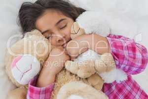 Girl sleeping with stuffed toys in bed