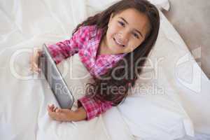 Young girl using digital tablet in bed