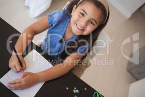 Portrait of a young smiling girl drawing on table
