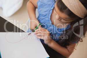 High angle close-up of a girl cutting chart paper