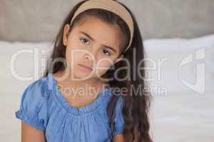 Close-up portrait of a sad young girl on bed