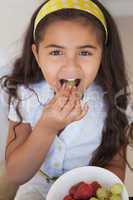 Close-up portrait of a smiling girl eating fruits