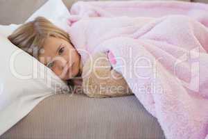 Young girl resting on sofa with stuffed toy