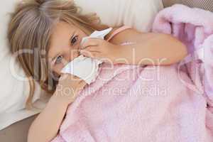 Girl suffering from cold as she lies in bed