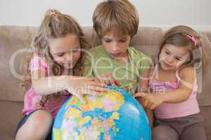Three kids with globe sitting in living room