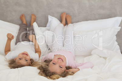 Portrait of two smiling kids lying in bed