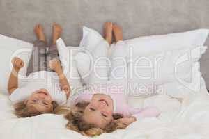 Portrait of two smiling kids lying in bed