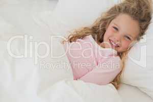 Smiling young girl resting in bed