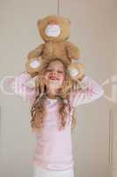 Portrait of happy girl holding stuffed toy over head