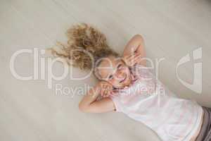 High angle portrait of a smiling girl lying on floor