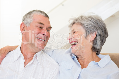 Retired couple sitting on couch smiling at each other