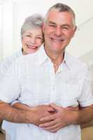 Retired couple smiling at camera and hugging