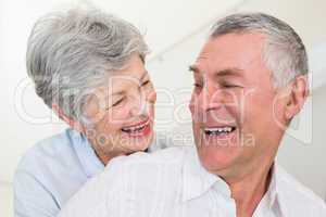 Retired couple smiling at each other and hugging