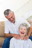 Man giving his senior wife a shoulder rub who is smiling at came