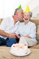 Senior couple sitting on couch celebrating a birthday