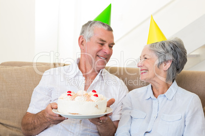 Senior couple sitting on couch celebrating a birthday