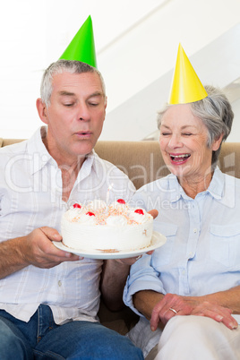 Senior couple sitting on couch celebrating a birthday