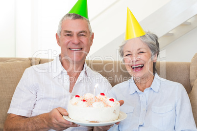 Senior couple sitting on couch celebrating a birthday