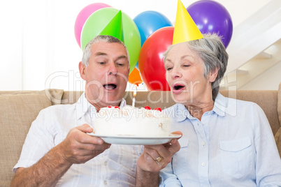 Senior couple sitting on couch celebrating a birthday