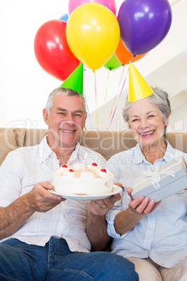 Senior couple sitting on couch celebrating a birthday