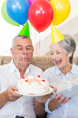 Senior couple sitting on couch celebrating a birthday