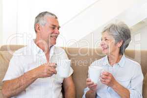Senior couple sitting on couch drinking coffee